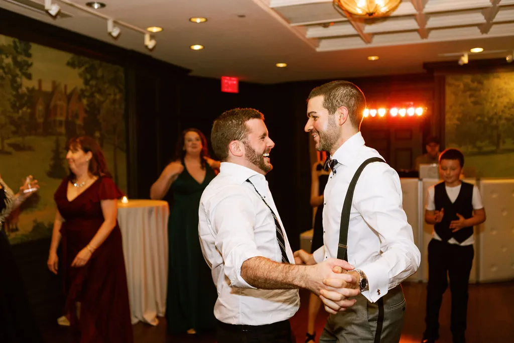 Mark and Michael dancing with guests at their wedding reception at the Inns of Aurora