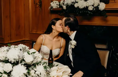 Bride and groom kissing at a table, Summer and Nicholas
