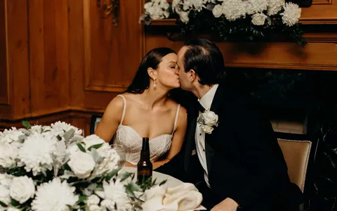 Bride and groom kissing at a table, Summer and Nicholas