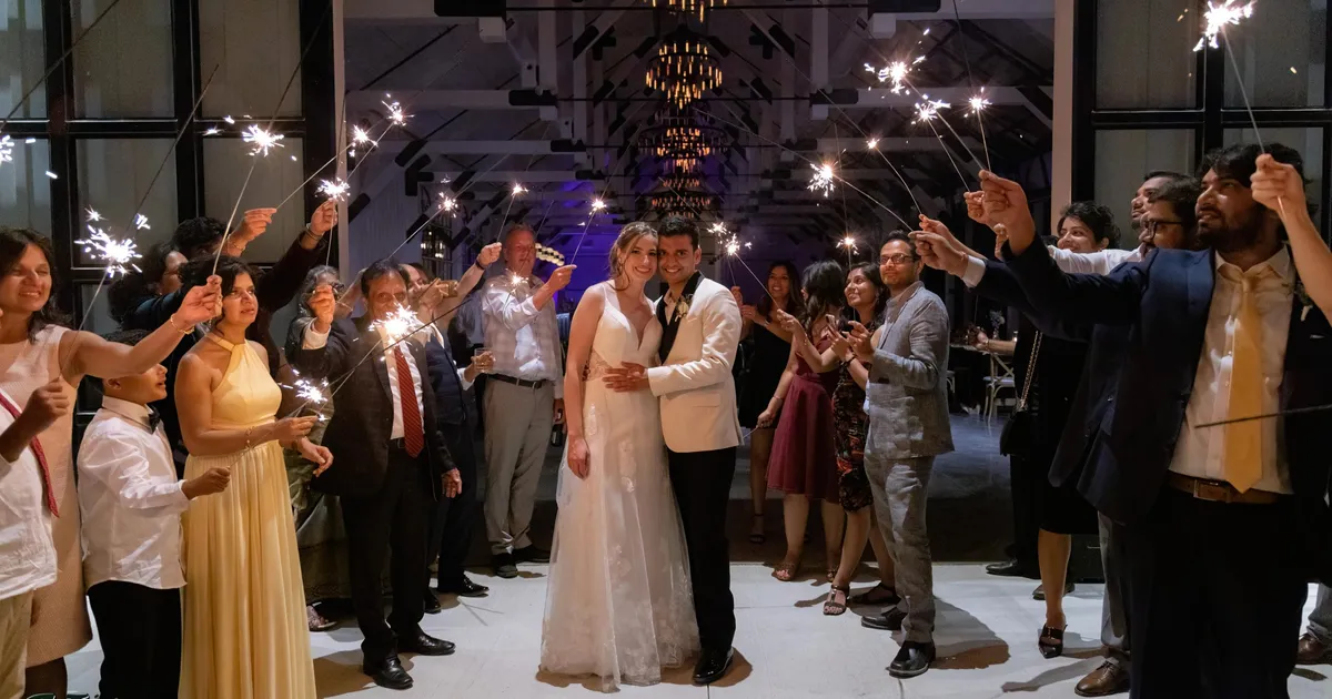 married couple with sparklers and guests