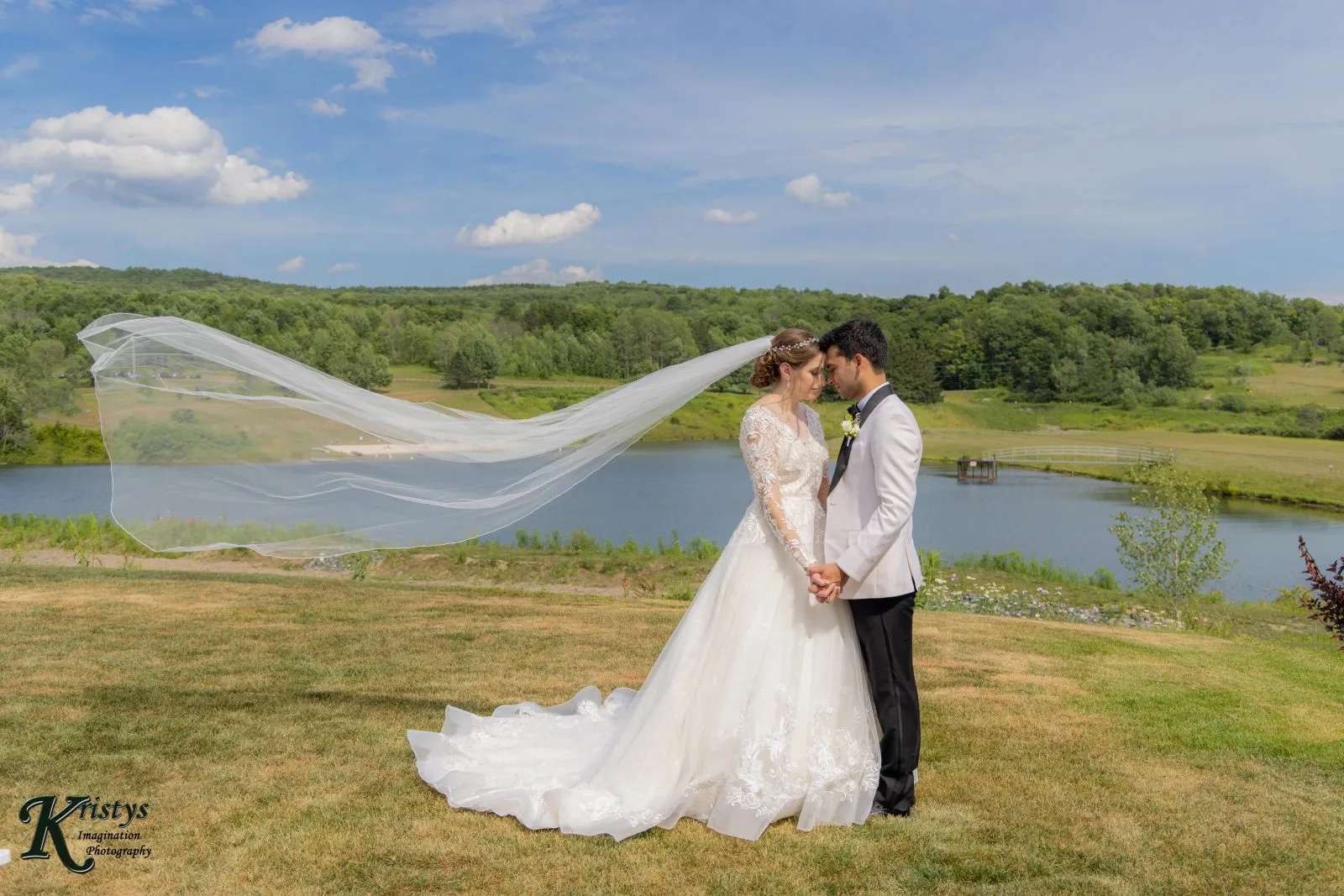 Danielle and Deepak near the lake with her veil blowing in the wind at Greek Peak